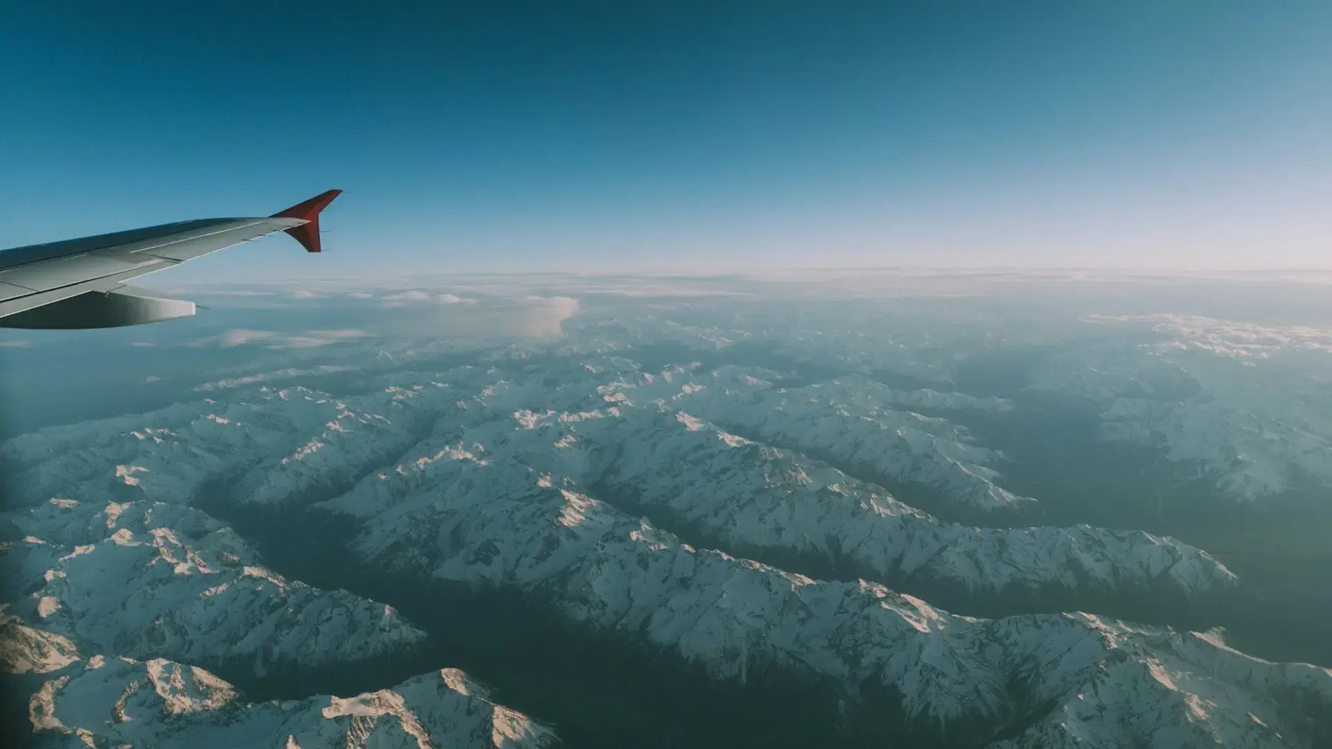 Aeroplane wing above snowy mountains