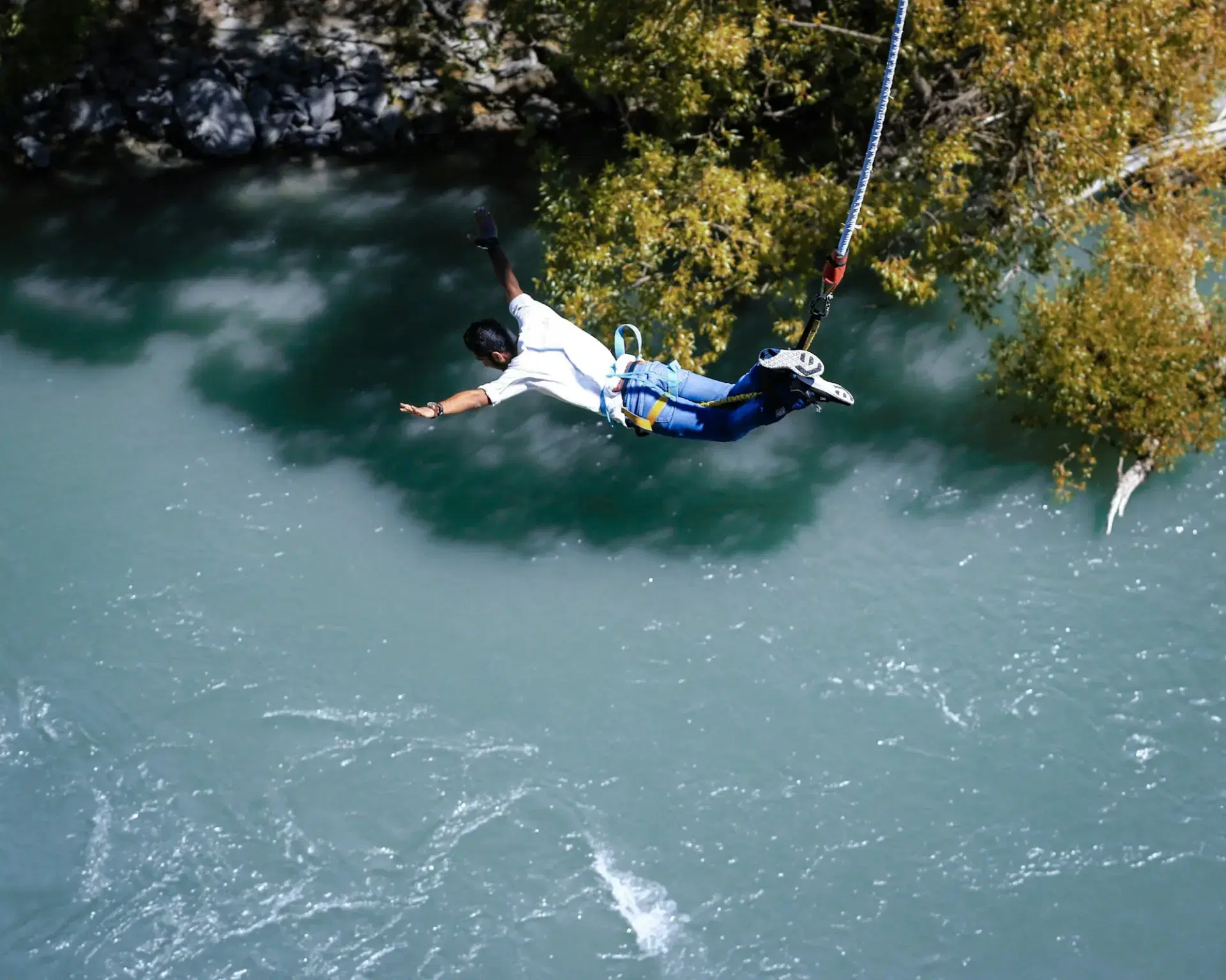 Bungee jumper plunging toward a river gorge