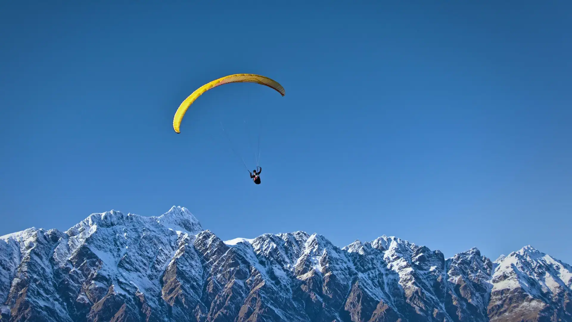 Paraglider soaring beside a mountain